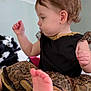 Brailee joined the competition — help win amazing prizes! toddler, child, baby, dress, black_clothing, gold_trim, sitting, foot, curly_hair, indoor, soft_surface, cute, young_child, profile_view, playful, infant, person, portrait, small_hand, focused