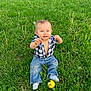 baby, ball, blue_eyes, child, cute, grass, greenery, happy, jeans, nature, outdoor, plaid_shirt, playful, sitting, smiling, socks, sunlight, toddler, tree, yellow_ball