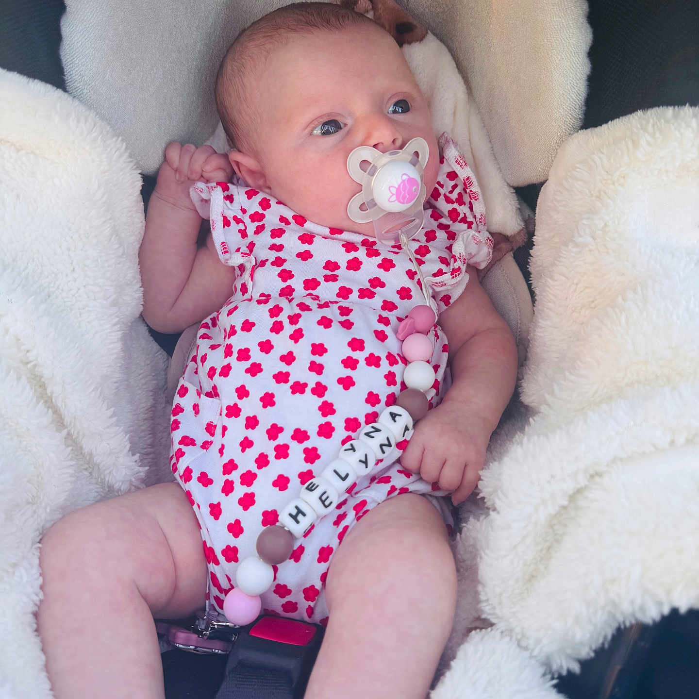 Hélyna a rejoint le concours — aidez-le/la à gagner de superbes lots ! baby, infant, pacifier, onesie, floral_pattern, bead_chain, car_seat, blanket, cozy, cute, child, newborn, pink, red, white, soft, comfort, portrait, clothing, seatbelt