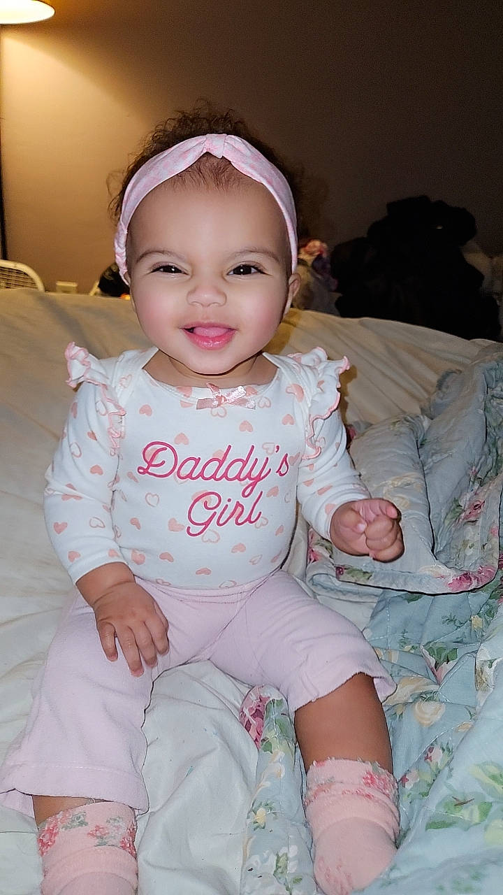 Sierra is registered to the contest to win money with this photo: baby, baby_toddler_clothing, cheek, chin, eye, face, facial_expression, finger, hairstyle, happy, human_body, iris, joy, lip, mouth, person, pink, product, skin, sleeve