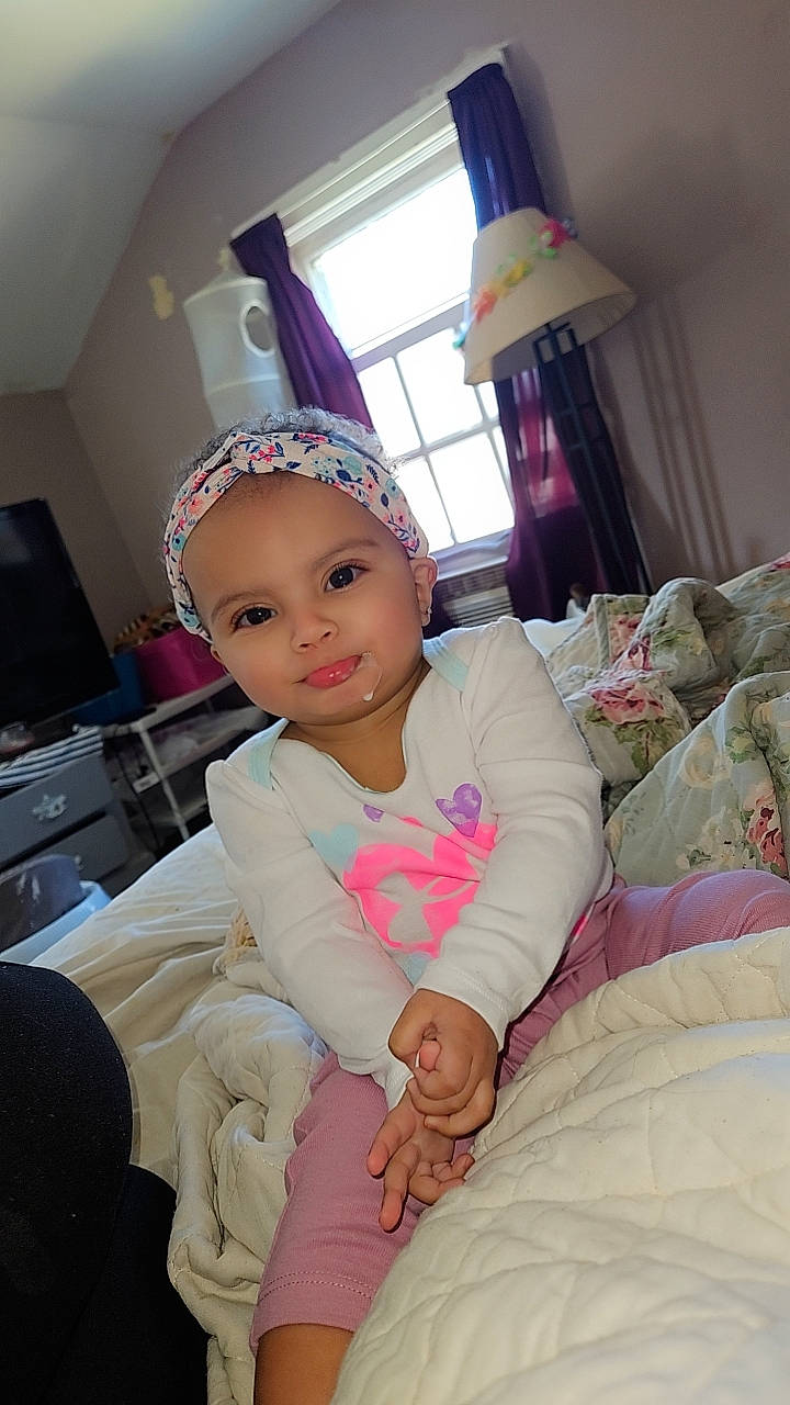 Sierra is registered to the contest to win money with this photo: baby, baby_toddler_clothing, comfort, costume, couch, event, fashion_accessory, fun, happy, headband, headpiece, headwear, lap, living_room, magenta, person, pink, room, sitting, television