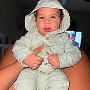 Byron Adriel is registered to the contest to win money with this photo: baby, child, hooded_clothing, infant, person, face, hands, legs, sitting, indoor, furniture, television, ceiling_fan, skin, cute, portrait, clothing, buttoned, expression, light