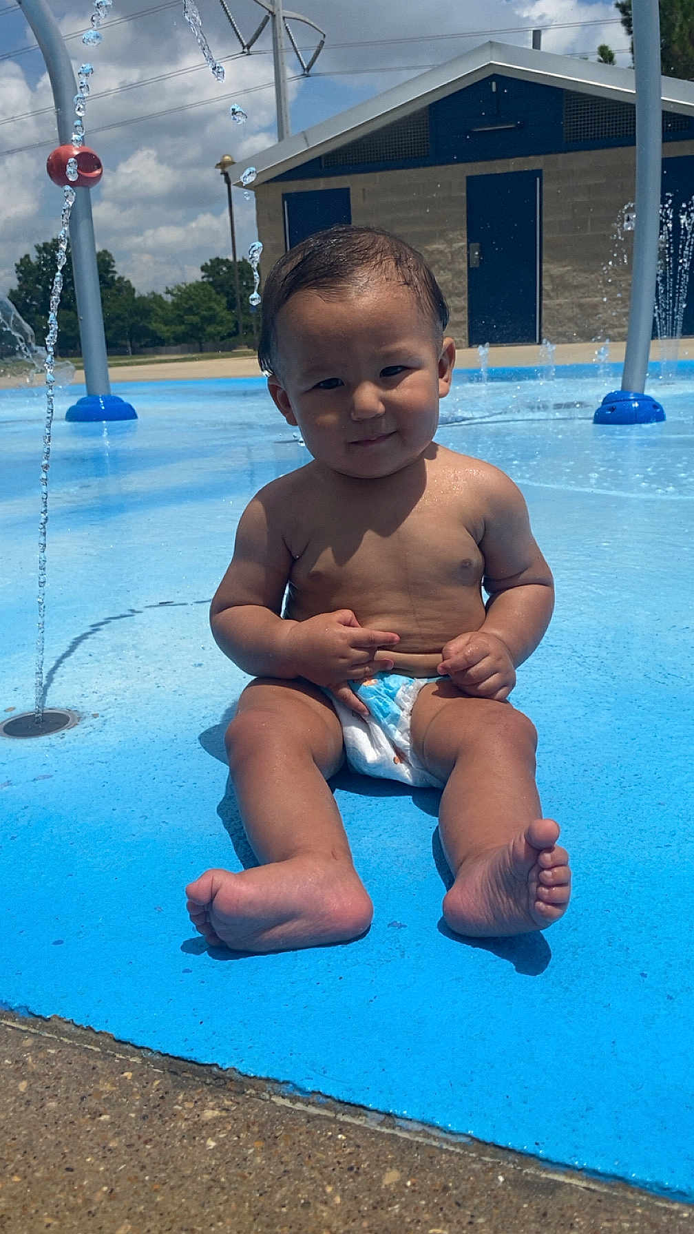Ezequiel Jio is registered to the contest to win money with this photo: toddler, child, diaper, water, splash_pad, outdoor, sunny, blue, play, summer, barefoot, water_jets, fun, park, skin, face, legs, feet, building, concrete