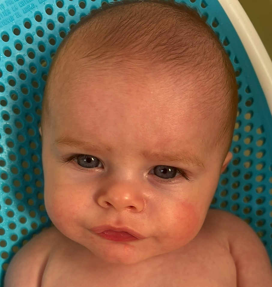 Nash is registered to the contest to win money with this photo: baby, face, head, skin, eyes, portrait, closeup, expression, child, infant, blue_background, curious, serious, young, human, cute, indoors, newborn, person, skin_texture