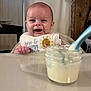 baby, bib, food, high_chair, smile, face, infant, table, spoon, jar, feeding, happy, cute, child, indoor, person, meal, messy, clothing, kitchen
