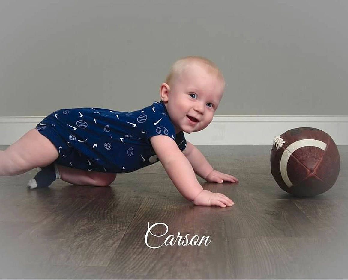 Carson joined the competition — help win amazing prizes! baby, baby_toddler_clothing, ball, child, door, finger, flash_photography, floor, flooring, foot, happy, hardwood, knee, pattern, person, sitting, sleeve, smile, t_shirt, toddler