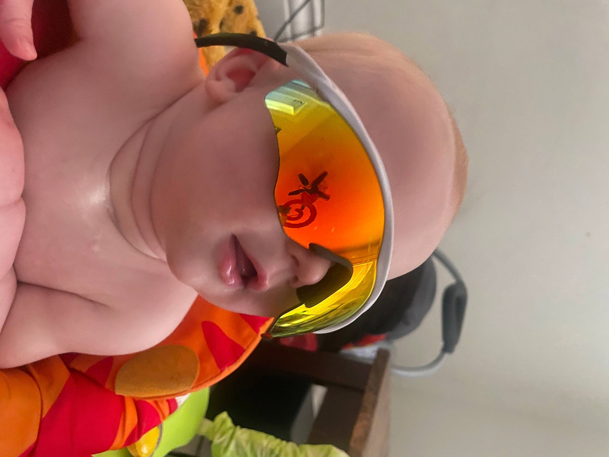 Carson is registered to the contest to win money with this photo: bathing, chest, child, chin, ear, eyewear, finger, fun, happy, head, headgear, mouth, neck, nose, orange, person, personal_protective_equipment, smile, toddler, toy