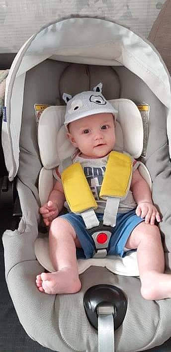 Tïago a rejoint le concours — aidez-le/la à gagner de superbes lots ! airline, arm, auto_part, baby, baby_carriage, baby_in_car_seat, baby_products, baby_safety, baby_toddler_clothing, car_seat, child, comfort, head_restraint, headwear, leg, person, personal_protective_equipment, seat_belt, sitting, thigh