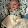 baby, sleeping, blanket, onesie, dinosaur_pattern, bedding, leaf_pattern, infant, peaceful, cozy, child, cute, portrait, resting, soft, knitted_blanket, bed, indoors, relaxation, comfort