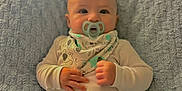 Rhyker is registered to the contest to win money with this photo: baby, bib, blanket, child, clothing, comfortable, cute, expression, face, hands, head, indoors, infant, pacifier, portrait, sitting, skin, small_hands, soft_texture, young