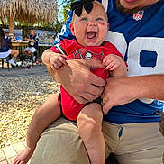 Sienna joined the competition — help win amazing prizes! baby, child, laughing, smiling, bow, red_clothing, sportswear, adult, holding, outdoor, sunny, people, hat, man, shorts, legs, feet, happy, daytime, background