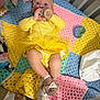 baby, blue, child, colorful_blanket, crib, crocheted_blanket, footwear, green, headband, indoor, infant, person, pink, plush_toy, toy, tutu, white_sandals, wooden_toy, yellow, yellow_dress