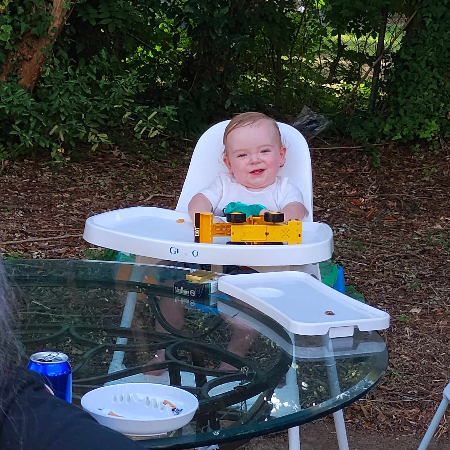 Haiden joined the competition — help win amazing prizes! baby, bodypart, can, chair, diningtable, face, finger, furniture, head, highchair, outdoors, person, photography, plant, portrait, summer, table, tin, tree, wood