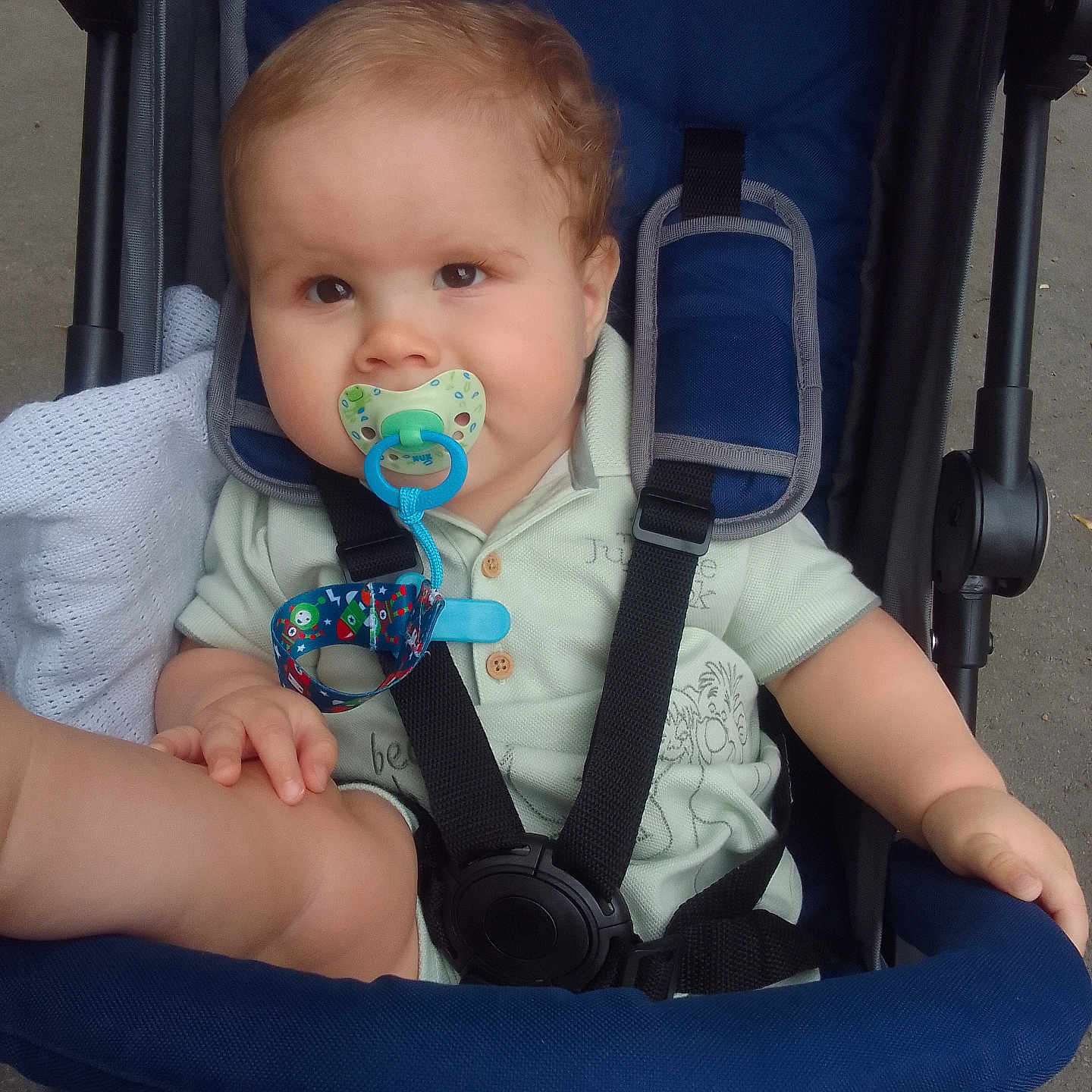 Louis joined the competition — help win amazing prizes! baby, blanket, blue, child, clothing, comfort, curly_hair, cute, expression, green, hands, infant, legs, outdoor, pacifier, safety_strap, seatbelt, sitting, stroller, toy_clip