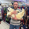animal, cute, dog, floor_tiles, golden_retriever, harness, holding, indoor, jeans, leash, man, people, pet_accessories, pet_store, puppy, shelf, shopping, signage, store_aisle, sweater