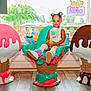 Stori Isabella is registered to the contest to win money with this photo: child, toddler, chair, ice_cream, toy, hair_clips, colorful, indoor, window, flooring, playful, smiling, cute, decor, furniture, person, seated, bright, plastic, fun
