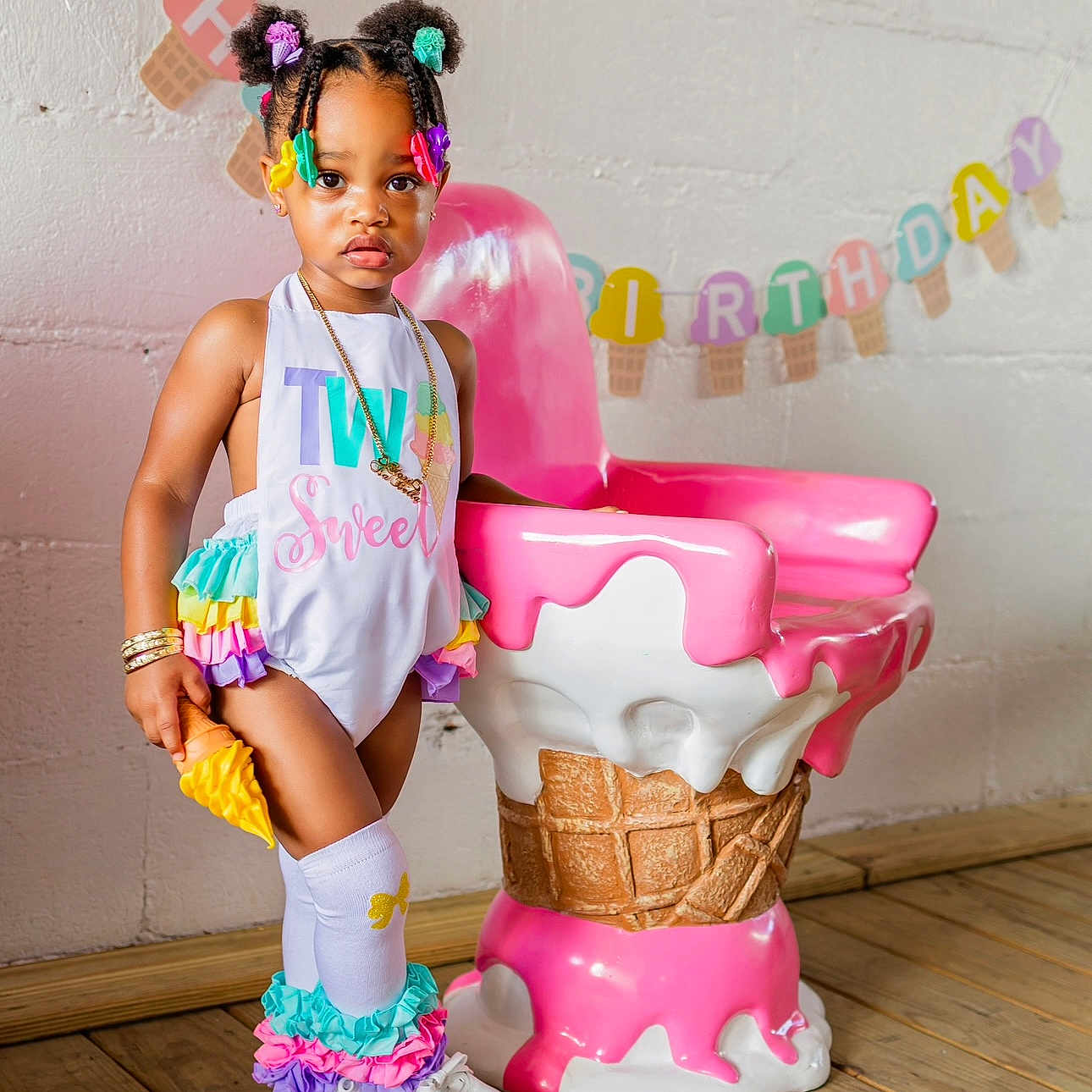 Stori Isabella is registered to the contest to win money with this photo: banner, birthday, chair, child, colorful_clothing, cute, decoration, fashion, hair_accessories, ice_cream_cone, indoor, party, playful, portrait, shoes, smiling, socks, toddler, wall, wooden_floor