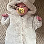Theo is registered to the contest to win money with this photo: baby, infant, pacifier, onesie, fluffy_clothing, bear_ears, carpet, cute, sleepwear, child, soft_texture, lying_down, small_hands, face, hooded_outfit, cozy, adorable, indoor, newborn, comfort