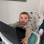 Jordan joined the competition — help win amazing prizes! baby, child, high_chair, laptop, sweater, indoor, curious, animal_print, face, hand, technology, furniture, mirror, window_blinds, person, expression, seated, keyboard, candid, home