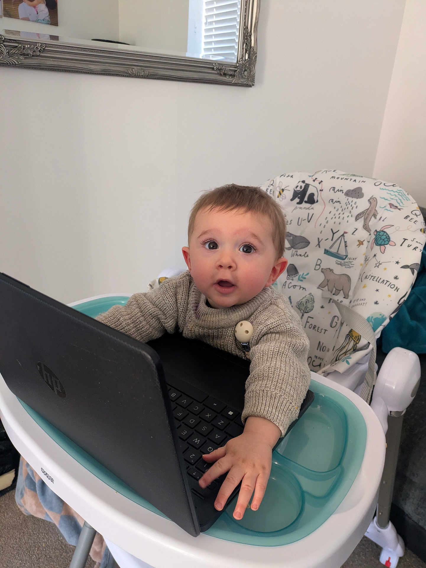 Jordan joined the competition — help win amazing prizes! baby, child, high_chair, laptop, sweater, indoor, curious, animal_print, face, hand, technology, furniture, mirror, window_blinds, person, expression, seated, keyboard, candid, home