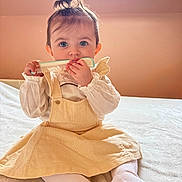 Alana participe au concours pour gagner de l'argent avec cette photo : baby, child, blue_eyes, comb, curly_hair, dress, yellow_dress, white_tights, indoor, bed, skylight, window, cute, infant, sitting, portrait, person, young_child, playful, soft_light