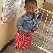 Honesti is registered to the contest to win money with this photo: child, denim_jacket, red_skirt, silver_shoes, heart_design, safety_gate, educational_poster, classroom, wooden_floor, earrings, afro_hairstyle, confident_pose, indoor, person, fashion, young_girl, cute, smiling, learning_environment, handwritten_text