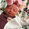 Shayla is registered to the contest to win money with this photo: newborn, baby, infant, sleeping, headband, pink_bow, white_sweater, floral_blanket, cute, portrait, child, soft_lighting, indoors, resting, peaceful, small, adorable, person, skin, laying_down