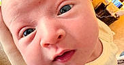 Shayla joined the competition — help win amazing prizes! baby, close_up, face, infant, child, skin, eyes, hand, yellow_clothing, pig_design, indoors, soft_skin, cute, portrait, person, head, expression, young, newborn, warm_lighting