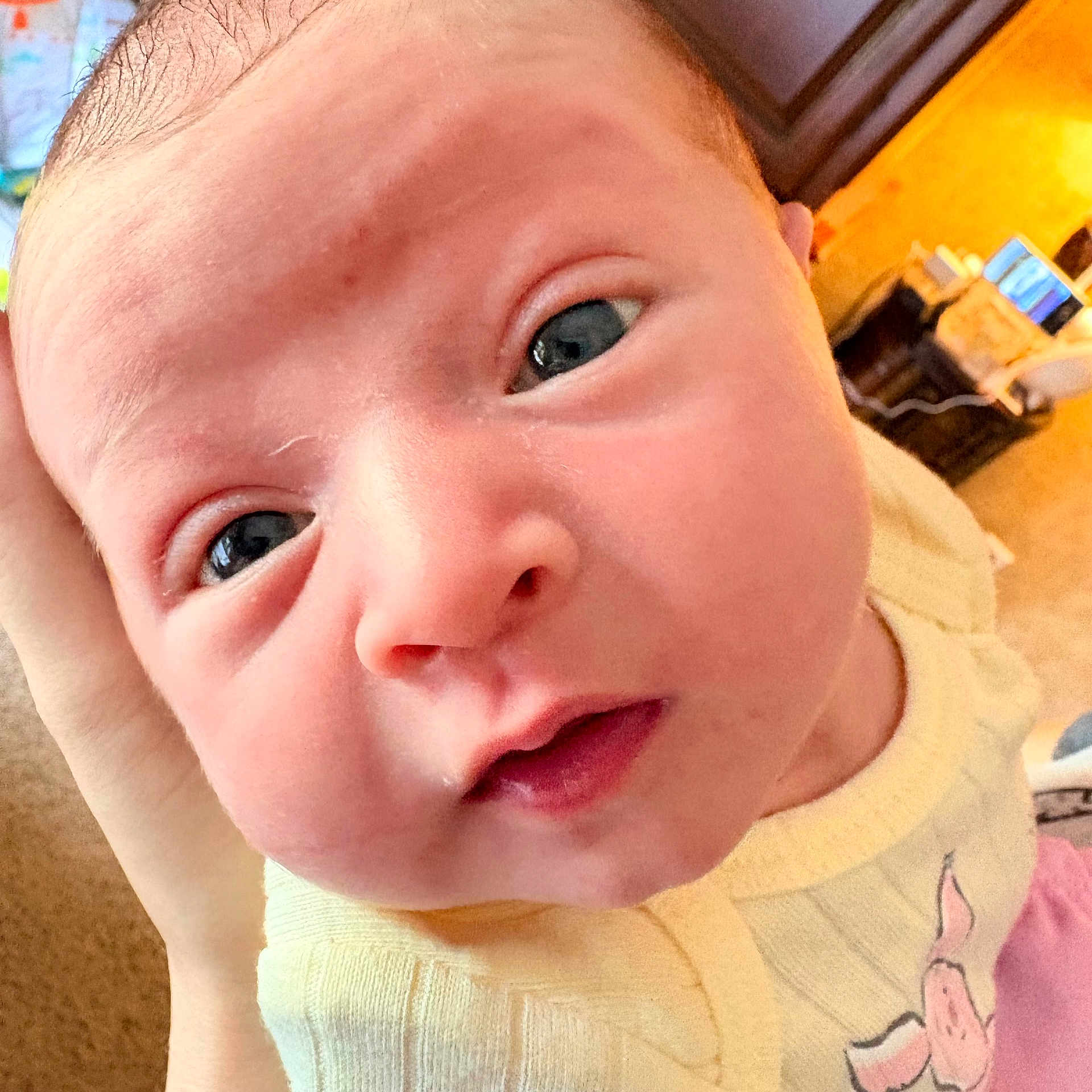 Shayla joined the competition — help win amazing prizes! baby, close_up, face, infant, child, skin, eyes, hand, yellow_clothing, pig_design, indoors, soft_skin, cute, portrait, person, head, expression, young, newborn, warm_lighting