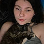 person, cat, sleeping_cat, indoor, cozy, closeup, portrait, relaxed, snuggling, dark_hair, casual_clothing, bedroom, resting, cuddling, animal, pet, comfort, young_adult, facial_piercing, soft_lighting