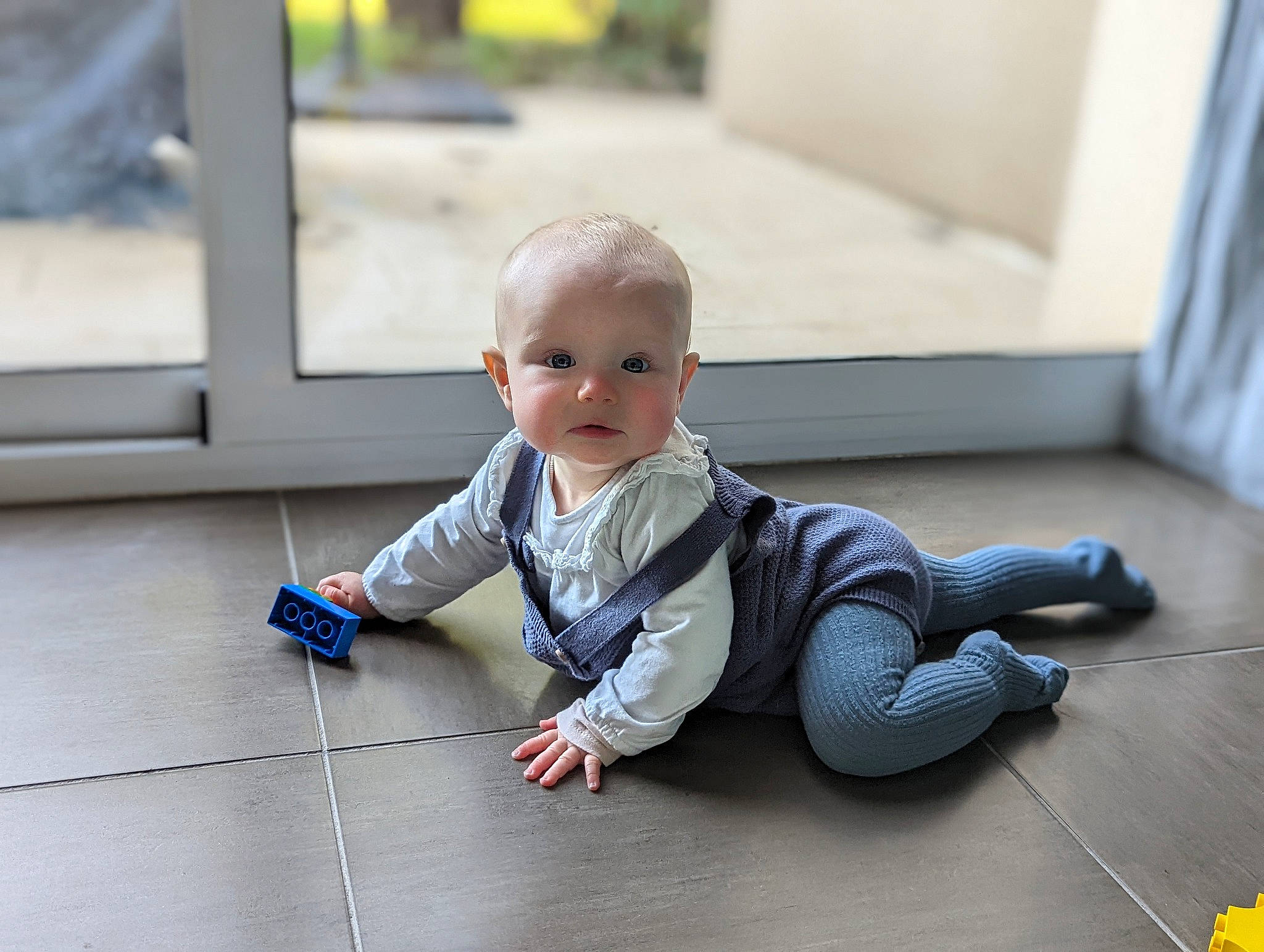 Naomi participe au concours pour gagner de l'argent avec cette photo : baby, baby_toddler_clothing, cheek, child, comfort, floor, flooring, foot, fun, grass, grey, happy, hardwood, pattern, person, room, sitting, skin, toddler, wood