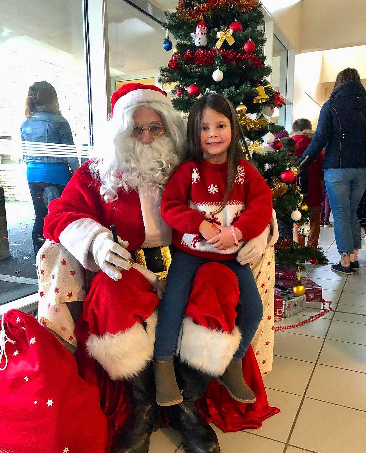 Léana participe au concours pour gagner de l'argent avec cette photo : beard, boot, christmas, christmas_decoration, christmas_eve, christmas_ornament, christmas_tree, event, facial_hair, fictional_character, fun, fur, happy, hat, holiday, joy, lap, outerwear, person, santa_claus