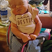 Evelyn is registered to the contest to win money with this photo: arm, baby, background, blanket, bottle, clothing, coca_cola, flowers, hand, indoor, infant, newborn, person, phone, plastic_bag, sleeping, striped_blanket, table, tattoo, water_bottle