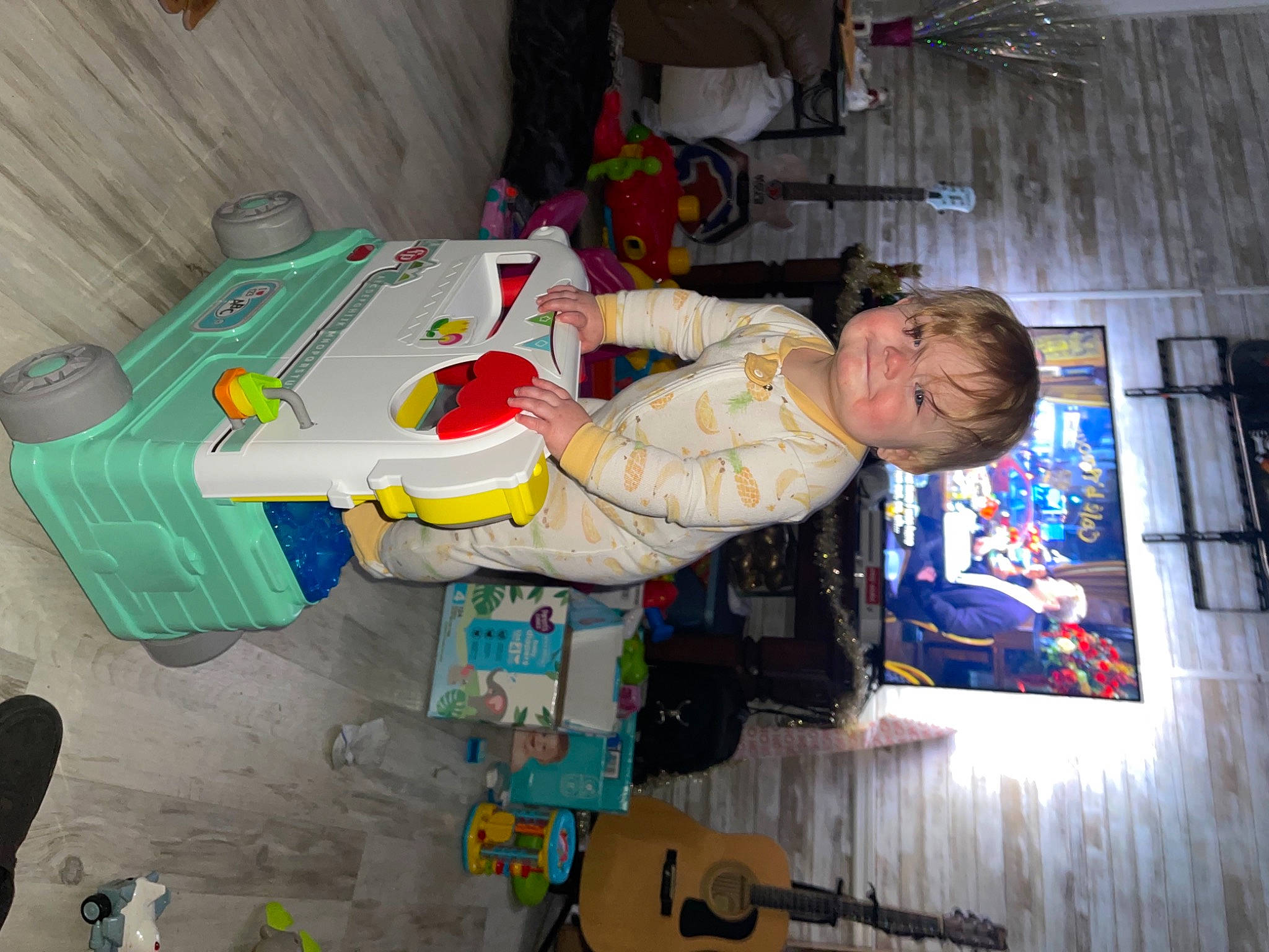 Kari is registered to the contest to win money with this photo: baby, baby_products, baby_toddler_clothing, child, fun, guitar, musical_instrument, person, plastic, room, smile, toddler