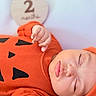 Eithan Milan is registered to the contest to win money with this photo: 2_months, baby, child, close_up, cute, face, hand, headwear, indoors, infant, milestone_sign, newborn, orange_clothing, peaceful, portrait, pumpkin, resting, skin, sleeping, soft_texture