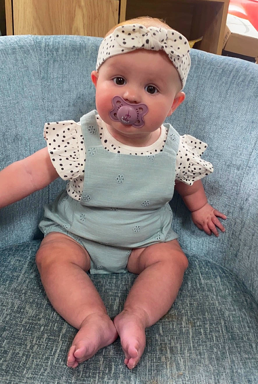 Luna is registered to the contest to win money with this photo: baby, baby_toddler_clothing, cap, cheek, child, chin, comfort, dress, eye, grass, headgear, headwear, iris, leg, lip, mouth, person, pink, skin, sleeve