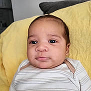 Legend is registered to the contest to win money with this photo: baby, child, couch, cozy, cute, expression, eyes, face, head, indoors, infant, person, pillow, portrait, relaxed, resting, skin, striped_clothing, yellow_pillow, young