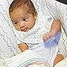 baby, blanket, child, clothing, comfort, cushion, cute, face, hand, indoors, infant, newborn, portrait, resting, seated, small, soft, striped, white, wrapped