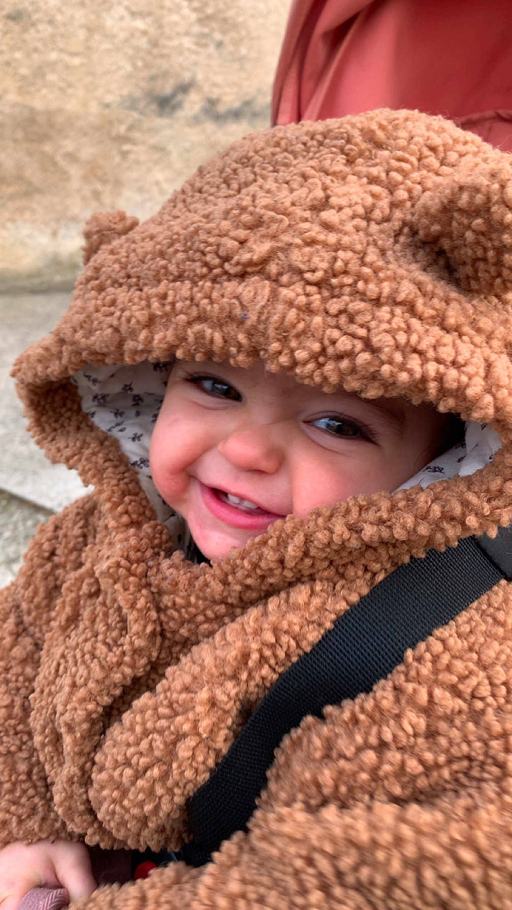 Elena a rejoint le concours — aidez-le/la à gagner de superbes lots ! child, toddler, baby, smile, hood, fuzzy_coat, teddy_texture, closeup, portrait, rosy_cheeks, teeth, stroller_strap, warm_clothing, outdoor, stone_wall, candid, cute, eyes, playful_expression, coat