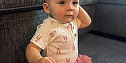 Audis is registered to the contest to win money with this photo: toddler, child, baby, cap, pink_clothing, shorts, carpet, couch, indoor, curious, sitting, person, casual_clothing, face, small_hand, living_room, soft_light, cute, young_child, portrait