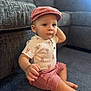 Audis is registered to the contest to win money with this photo: toddler, child, baby, cap, pink_clothing, shorts, carpet, couch, indoor, curious, sitting, person, casual_clothing, face, small_hand, living_room, soft_light, cute, young_child, portrait