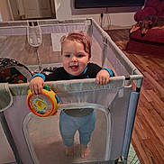 Alexander joined the competition — help win amazing prizes! toddler, child, baby, smiling, standing, playpen, toy, colorful_toy, indoors, living_room, dog, sleeping_dog, recliner, wood_floor, rug, halloween, pumpkin, television, furniture, portrait