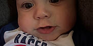 Kai is registered to the contest to win money with this photo: baby, infant, face, eyes, mouth, shirt, clothing, car_print, closeup, portrait, child, cute, expression, skin, head, indoors, person, young, sitting, couch
