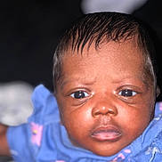 Nadia is registered to the contest to win money with this photo: baby, infant, face, closeup, blue_clothing, pink_flowers, skin, eyes, hand, portrait, child, cute, young, expression, person, indoors, human, head, newborn, baby_girl