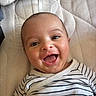 baby, smiling, happy, infant, striped_clothing, face, portrait, lying_down, mattress, cute, child, young, skin, head, eyes, mouth, cheeks, expression, indoor, person