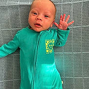 Hunter joined the competition — help win amazing prizes! baby, infant, onesie, teal, smiling, hand_wave, face, blanket, texture, cute, newborn, portrait, lying_down, expression, child, small_hand, clothing, indoor, happy, person