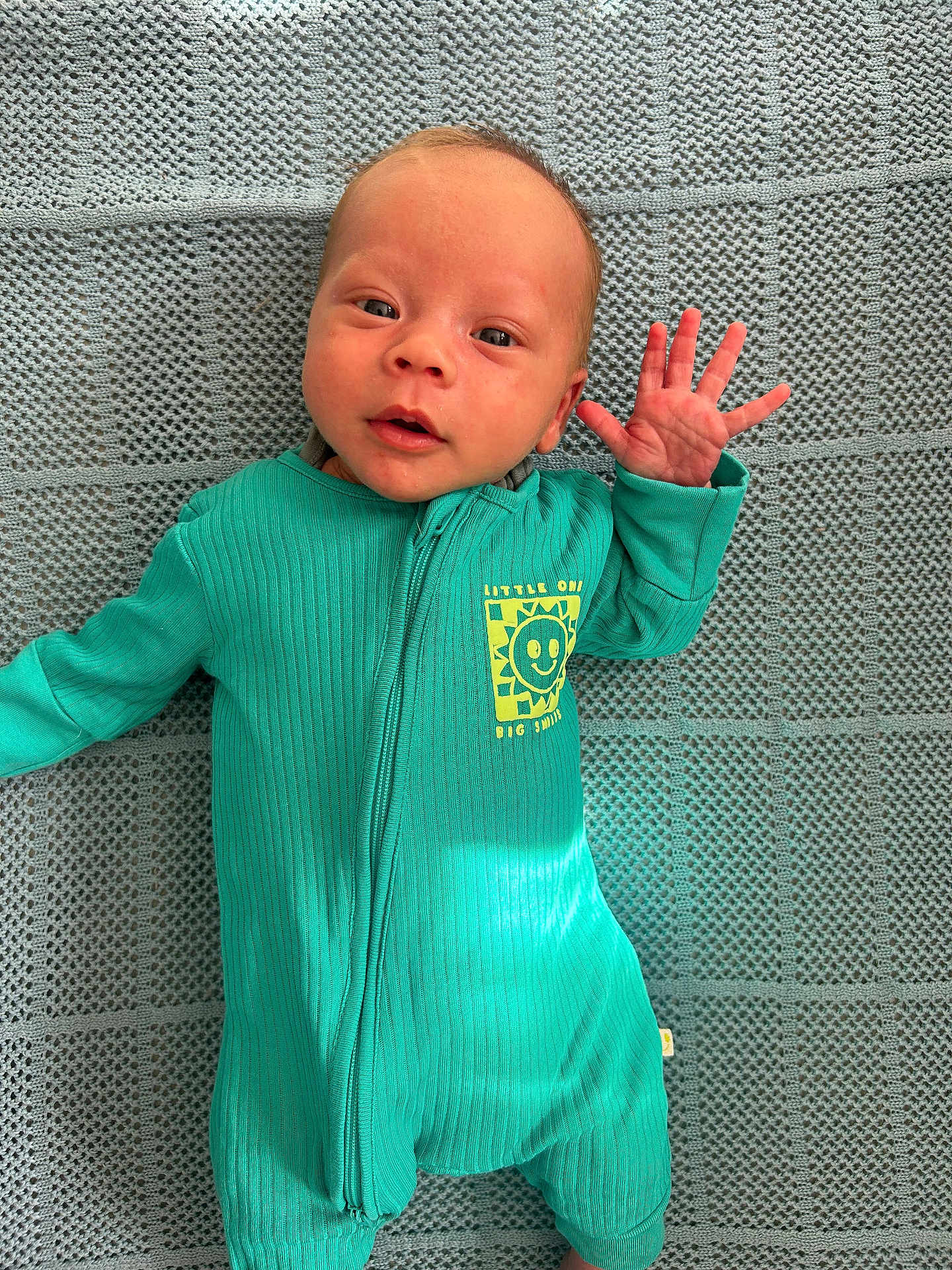 Hunter joined the competition — help win amazing prizes! baby, infant, onesie, teal, smiling, hand_wave, face, blanket, texture, cute, newborn, portrait, lying_down, expression, child, small_hand, clothing, indoor, happy, person