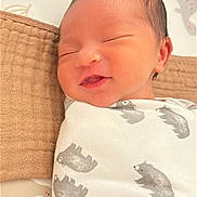 Hezekiah is registered to the contest to win money with this photo: newborn, baby, infant, sleeping, smiling, wrapped, blanket, bear_pattern, cushion, nursery, soft_lighting, cute, face, head, peaceful, indoors, young_child, resting, cozy, portrait