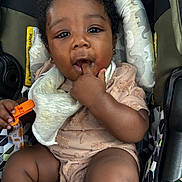 Alexanderisaac is registered to the contest to win money with this photo: baby, child, car_seat, infant, cute, fingers_in_mouth, bib, clothing, curly_hair, seatbelt, texture, face, person, skin, hand, legs, black_hair, expression, indoor, sitting