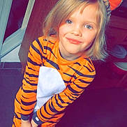 Elena a rejoint le concours — aidez-le/la à gagner de superbes lots ! child, tiger_costume, orange, stripes, onesie, indoor, smile, happy, cute, headband, ears, blonde_hair, playful, portrait, person, floor, door, cabinet, home, costume